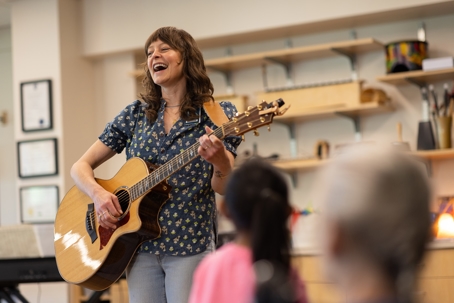 Hilary Camino playing the guitar while signing