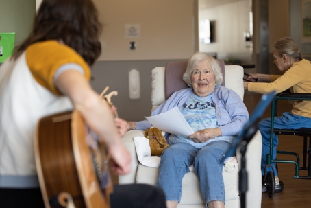 Hilary playing guitar with resident at Sage Living