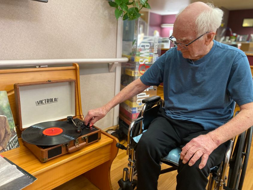 Elderly man listening to music on record player